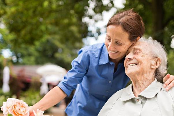 Senior woman sitting on a wheelchair with caregiver