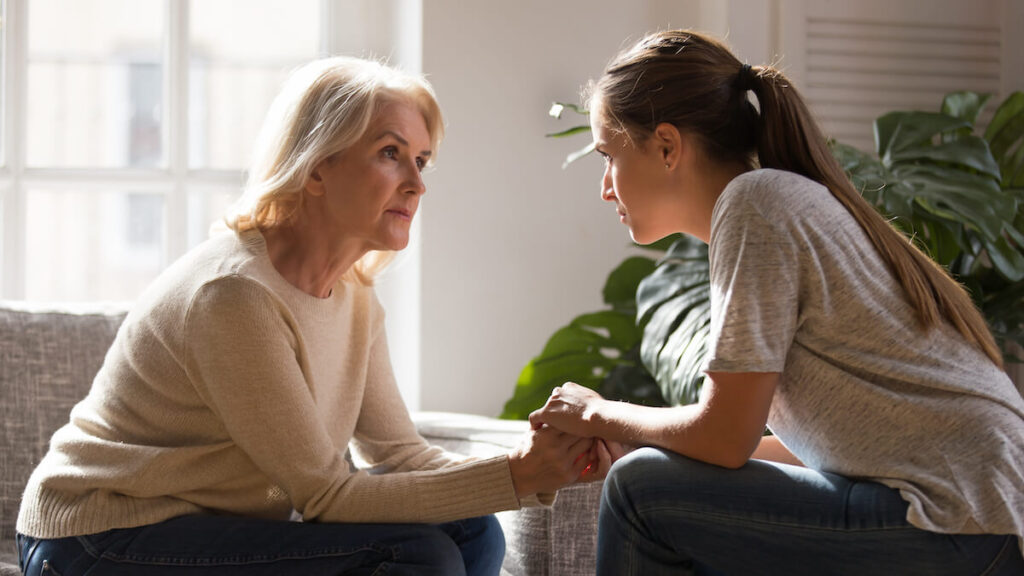 Adult daughter holding hands with her mother and talking