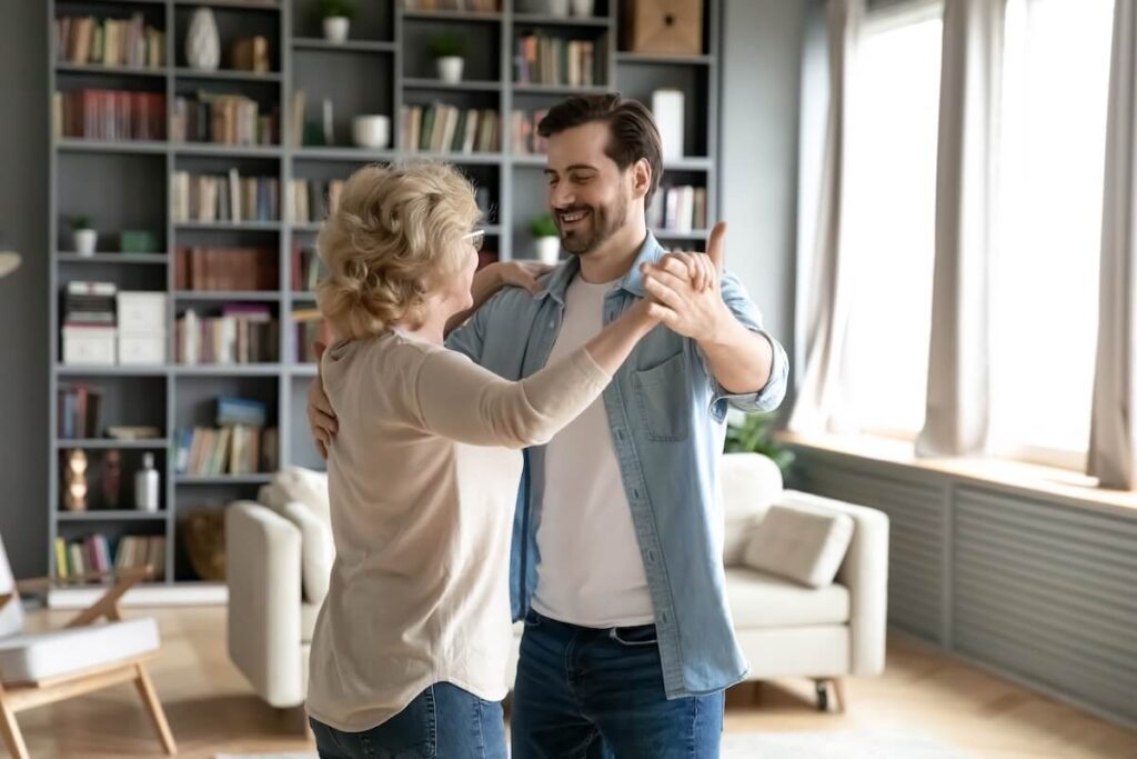 Adult son and her elderly mother dancing together
