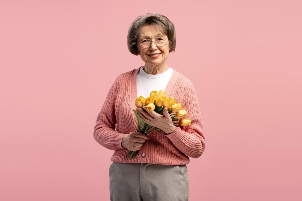 Happy older woman holding yellow flowers