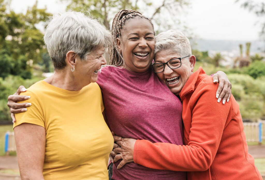 A group of older women laughing and hugging