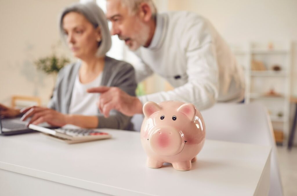 A couple of seniors doing finance math with a piggy bank in the front