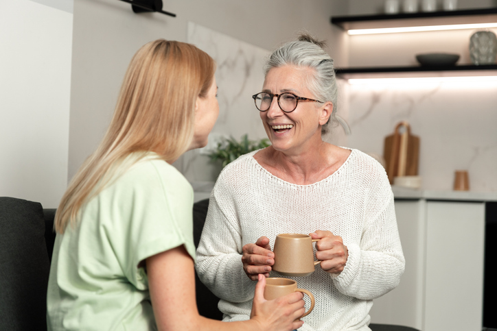 Elderly mother and adult daughter share a happy moment in their cozy apartment