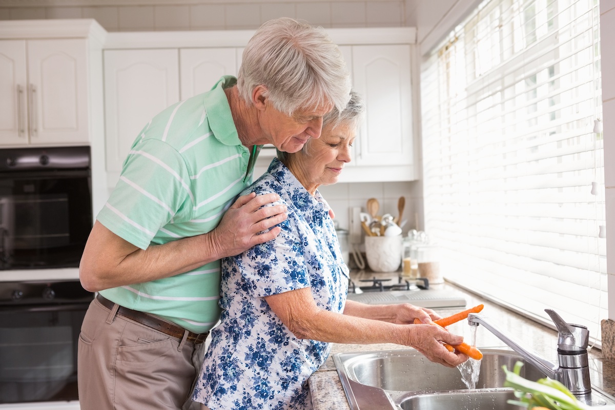 Senior couple washing vegetables at sink